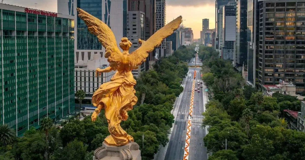 Ángel dorado en columna con fondo urbano al atardecer, simbolizando justicia y reforma legal.