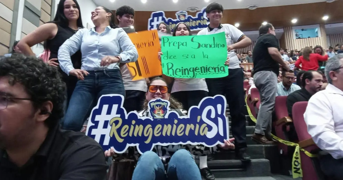 Personas en un evento de la UAS sosteniendo carteles de apoyo a la reingeniería financiera.