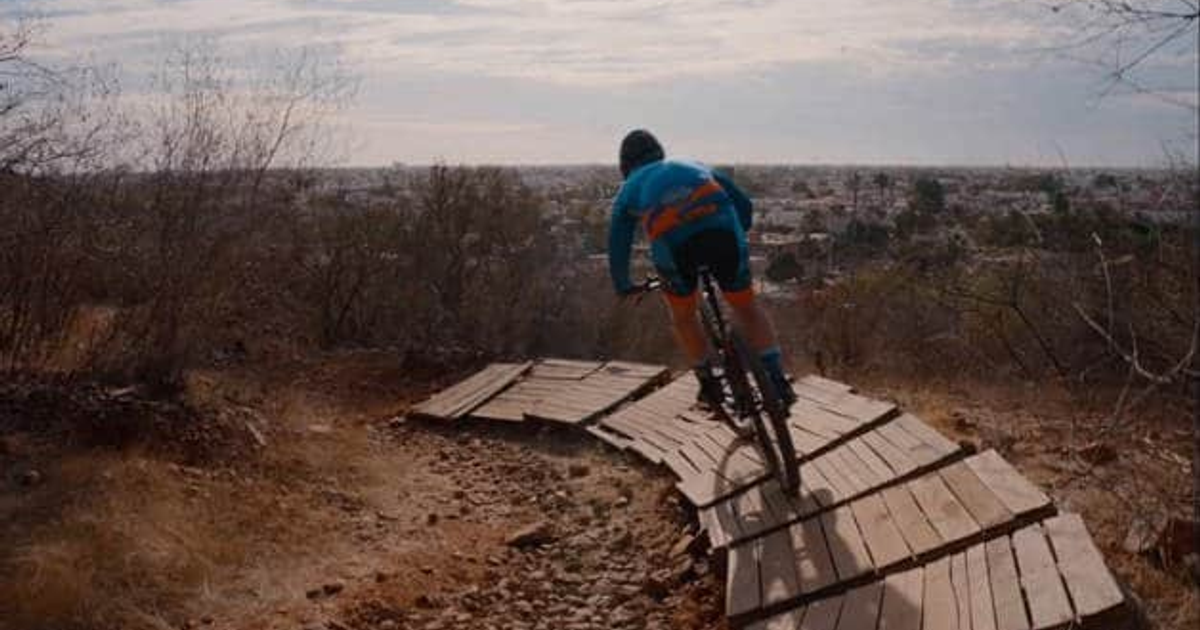 Ciclista en camino de montaña con vista a la ciudad