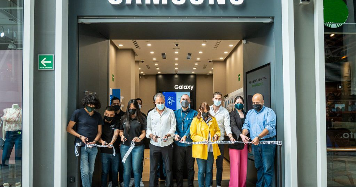 Inauguración de tienda Samsung en Ciudad de México con personas sosteniendo una cinta y productos electrónicos visibles en el interior.