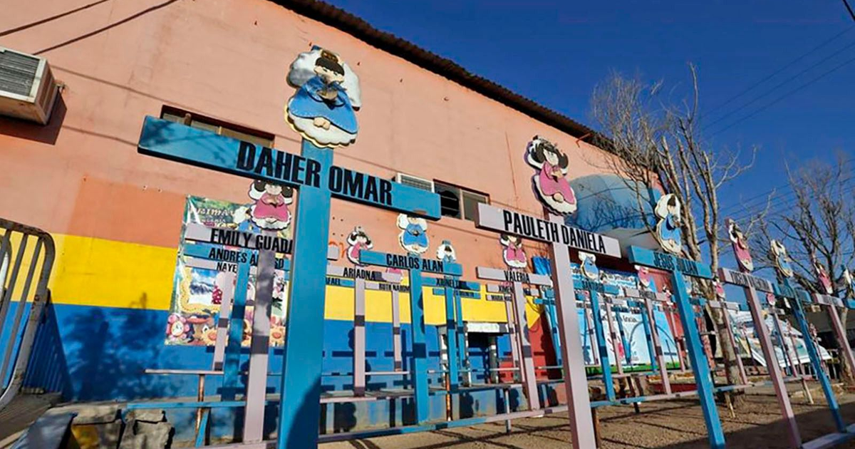 Edificio escolar colorido con postes decorativos y árboles sin hojas en un día soleado.