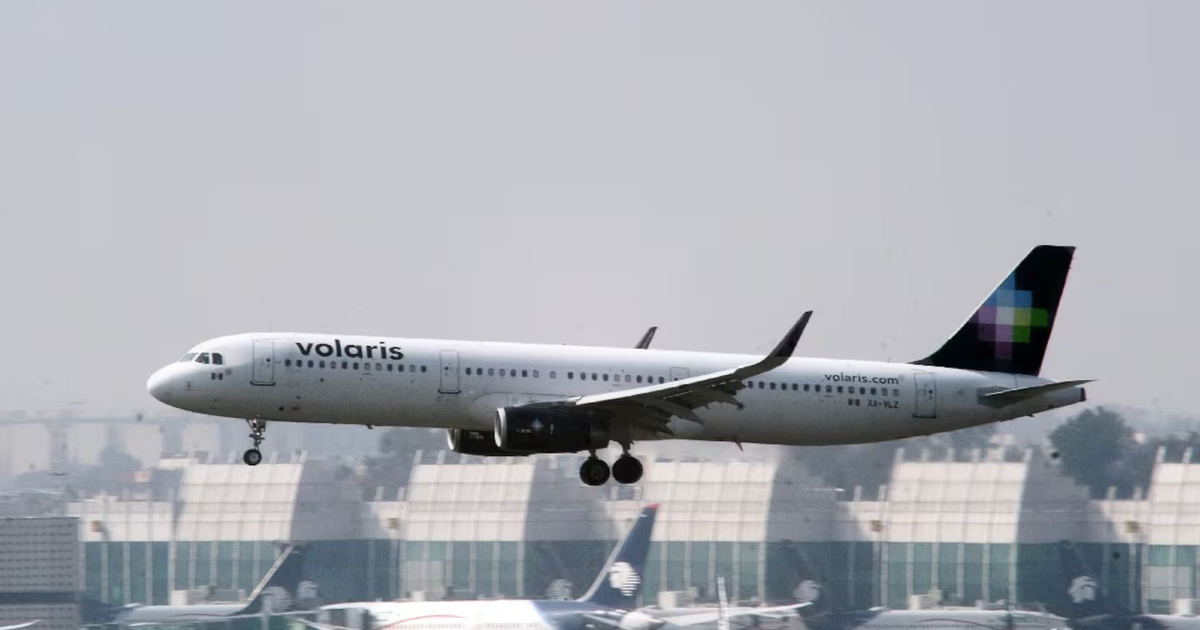 Avión de Volaris aterrizando en el AICM con terminal de fondo