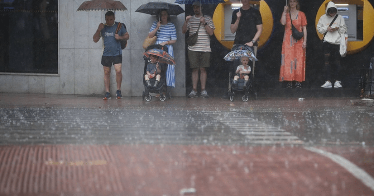 Personas con paraguas en la acera durante una fuerte lluvia en Mazatlán