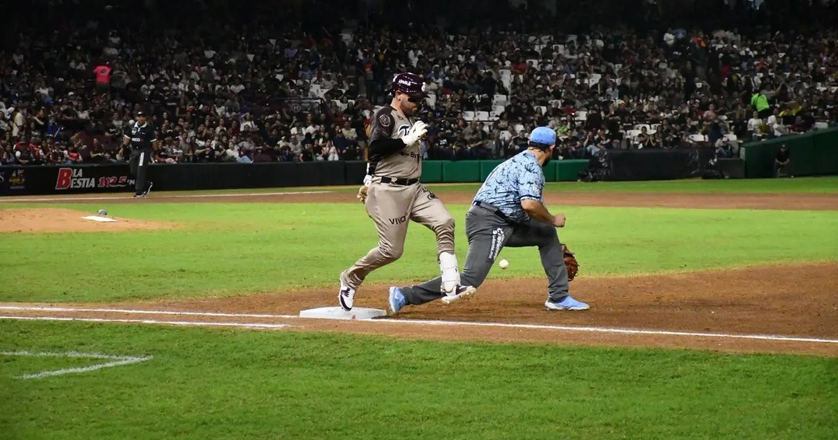 Jugador de béisbol corriendo hacia la primera base durante el partido Tomateros vs. Algodoneros, con el público animando en el estadio.