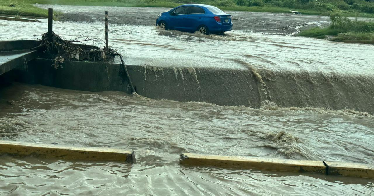 Carretera inundada en Mazatlán con vehículo azul sumergido tras lluvias por tormenta Raymond