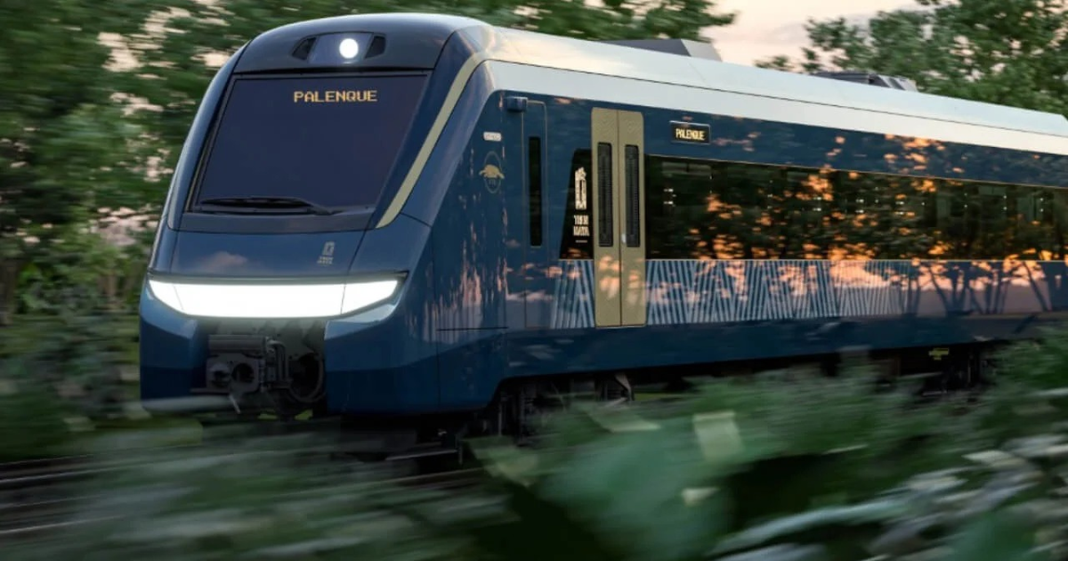 Tren Maya azul en movimiento con 'PALENQUE' en el frente, rodeado de vegetación.