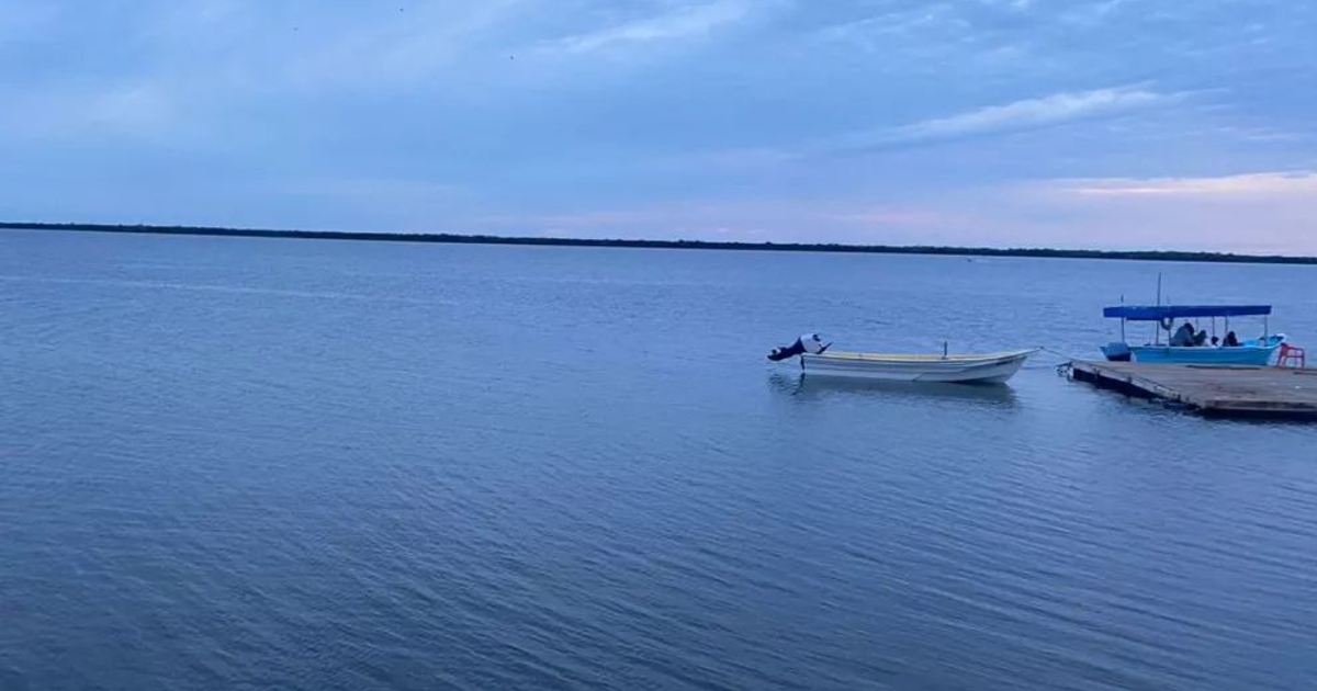 Cuerpo de agua tranquilo con barcos y cielo nublado, reflejando la calma buscada por pescadores en Altata.