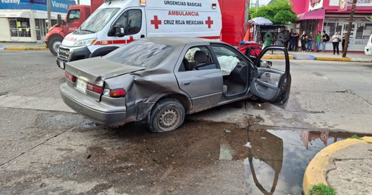 Auto gris dañado con puerta abierta y ambulancia de la Cruz Roja en un accidente en Los Mochis