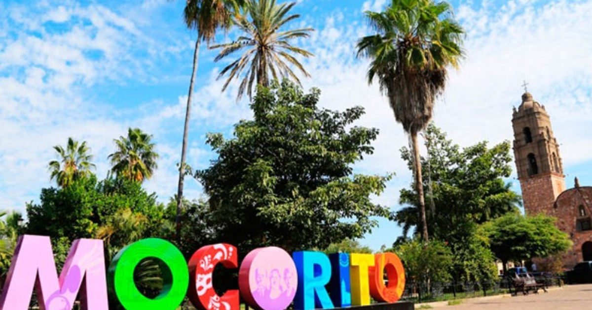 Vista del paisaje urbano de Mocorito con letras coloridas y una iglesia al fondo