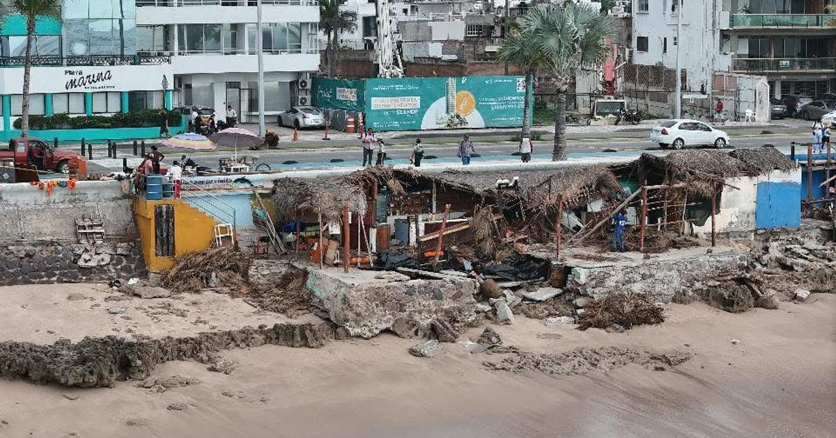 Zona costera en ruinas en Mazatlán tras marejadas, con estructuras dañadas y desechos en la playa.