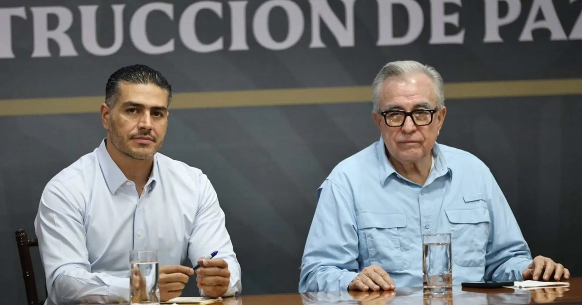 Dos hombres en una reunión de seguridad en Mazatlán, con fondo de 'Construcción de Paz'.
