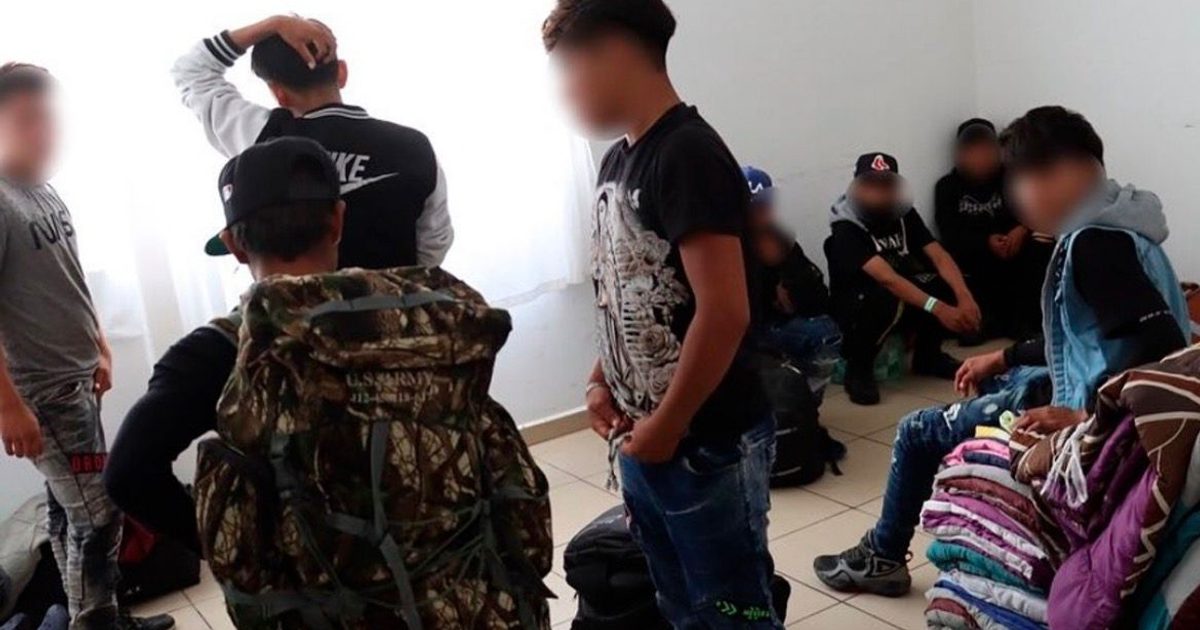 Grupo de jóvenes rescatados en Ahome, Sinaloa, en una habitación iluminada por la luz natural, rodeados de mochilas y ropa.