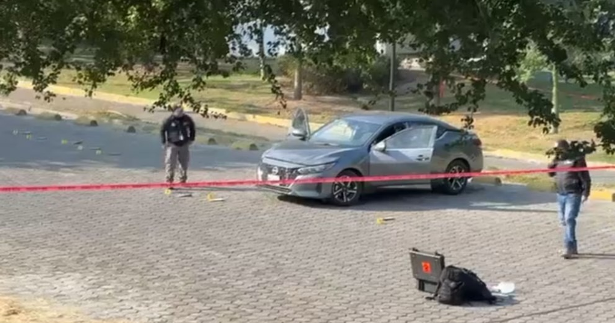 Automóvil gris y oficial investigando en Zapopan, coche abandonado por agentes desaparecidos