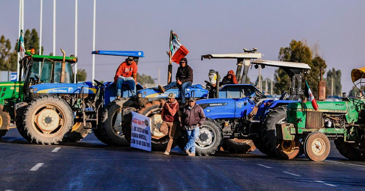 Tractores bloqueando carretera en protesta por deuda agrícola con bandera mexicana.