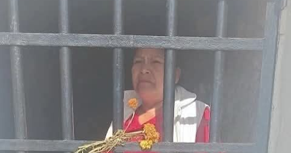 Alejandra Jiménez, síndica de Oaxaca, tras rejas con flores, simbolizando resistencia.