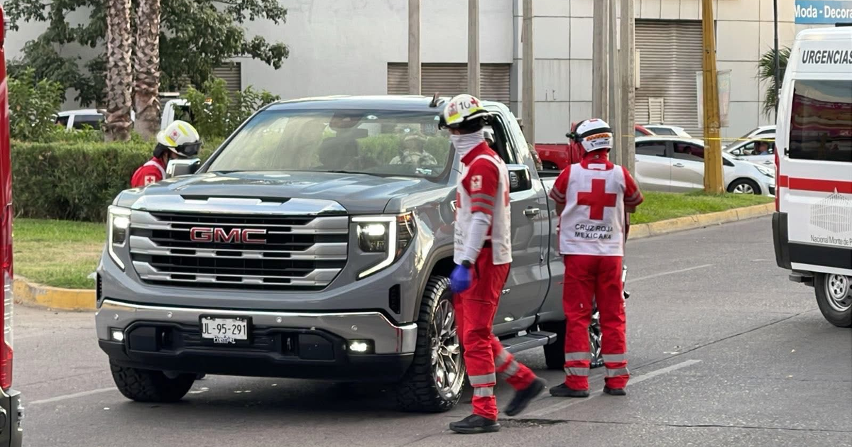 Trabajadores de la Cruz Roja Mexicana asistiendo a una camioneta GMC gris en Culiacán tras un ataque armado.