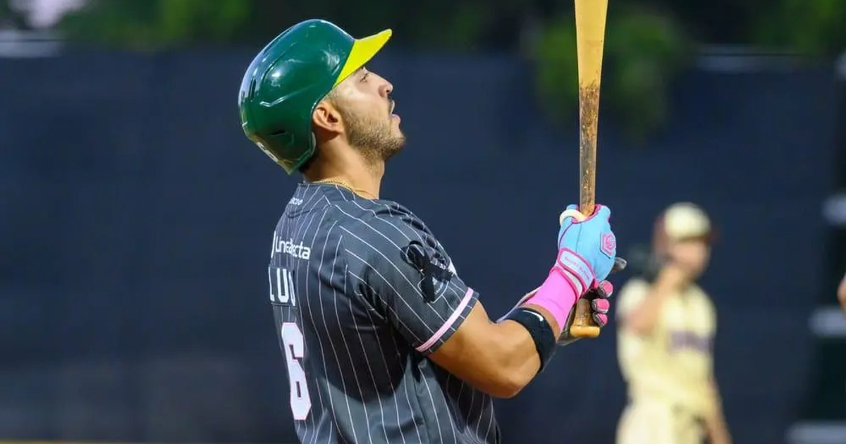 Jugador de béisbol de Los Cañeros de Los Mochis a punto de batear, con casco verde y guante rosa.
