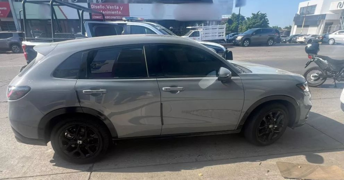 Automóvil gris estacionado en Culiacán con tráfico y edificio al fondo