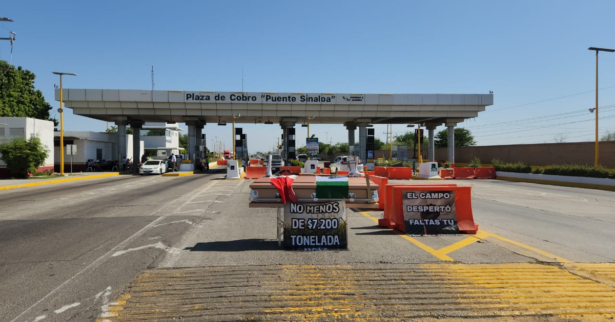 Protesta de productores agrícolas en la Plaza de Cobro 'Puente Sinaloa' con letreros y barricadas en un día soleado.