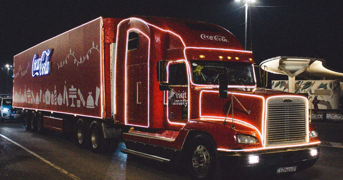Camión Coca-Cola iluminado en carretera nocturna, parte de las Caravanas Navideñas.