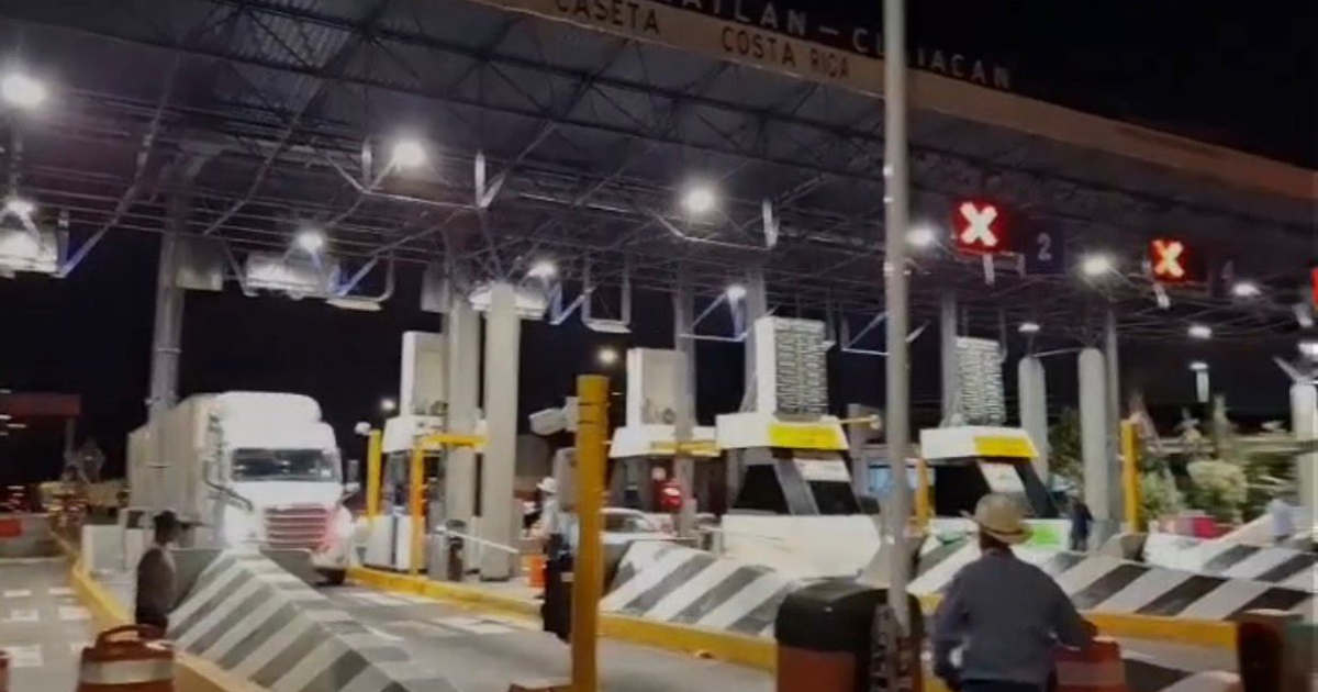 Caseta de peaje Costa Rica en Culiacán tomada durante paro agrícola. Vehículos y camión de carga presentes. Trabajador con sombrero visible.
