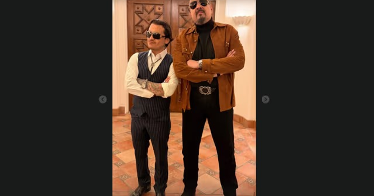 Dos personas con estilos contrastantes en la ceremonia del Latin Grammy 2025, una con traje de rayas y otra con chaqueta marrón, ambas con lentes oscuros.