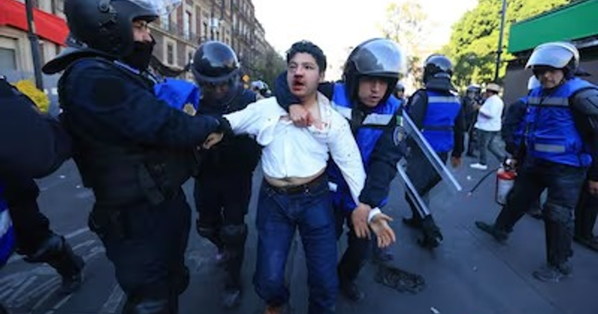 Hombre herido siendo sujetado por policías durante protesta en Ciudad de México