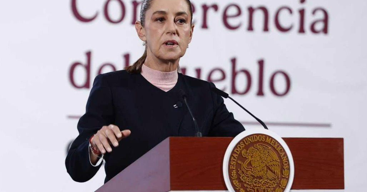 Claudia Sheinbaum hablando en un podio durante la Conferencia del Pueblo, con un escudo nacional de fondo.