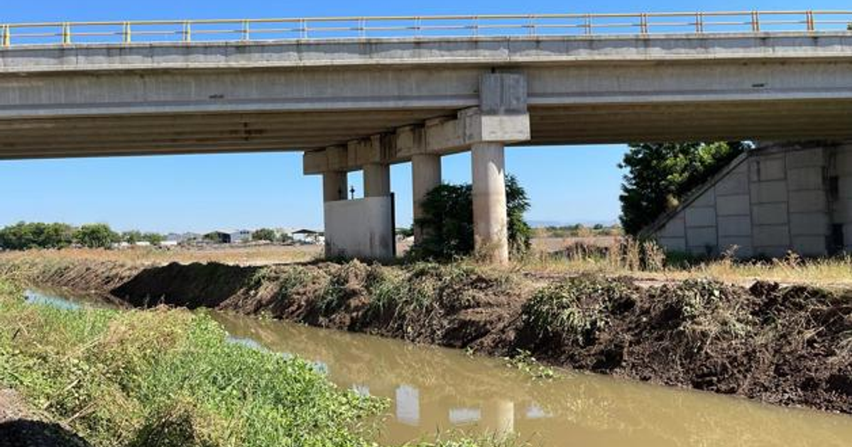 Puente elevado sobre canal en Culiacán, Sinaloa, con vegetación y canal de agua.