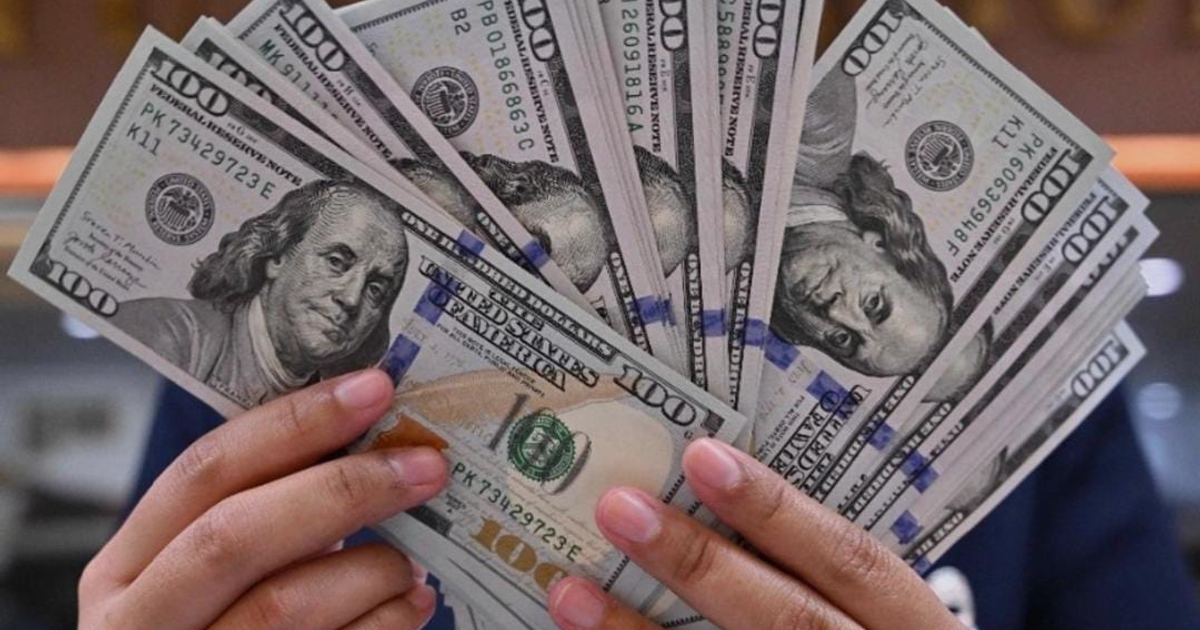 Persona sosteniendo billetes de cien dólares con la imagen de Benjamin Franklin, relacionado con la cotización del dólar en Sinaloa.