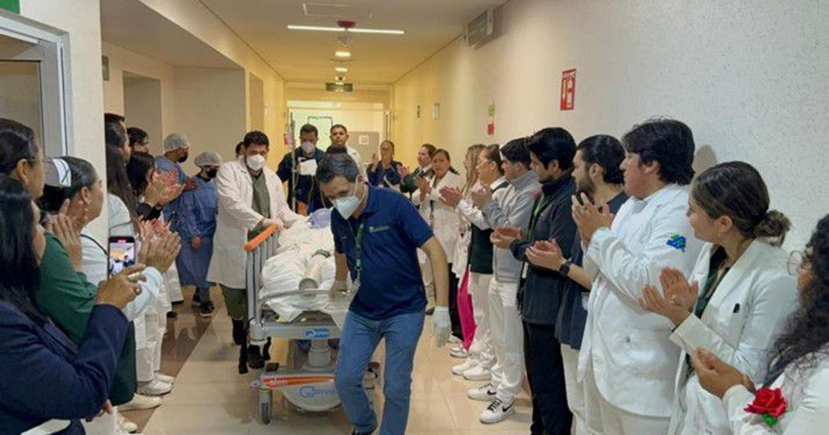 Medical staff applauding as a patient is wheeled through a hospital corridor, celebrating organ donation.