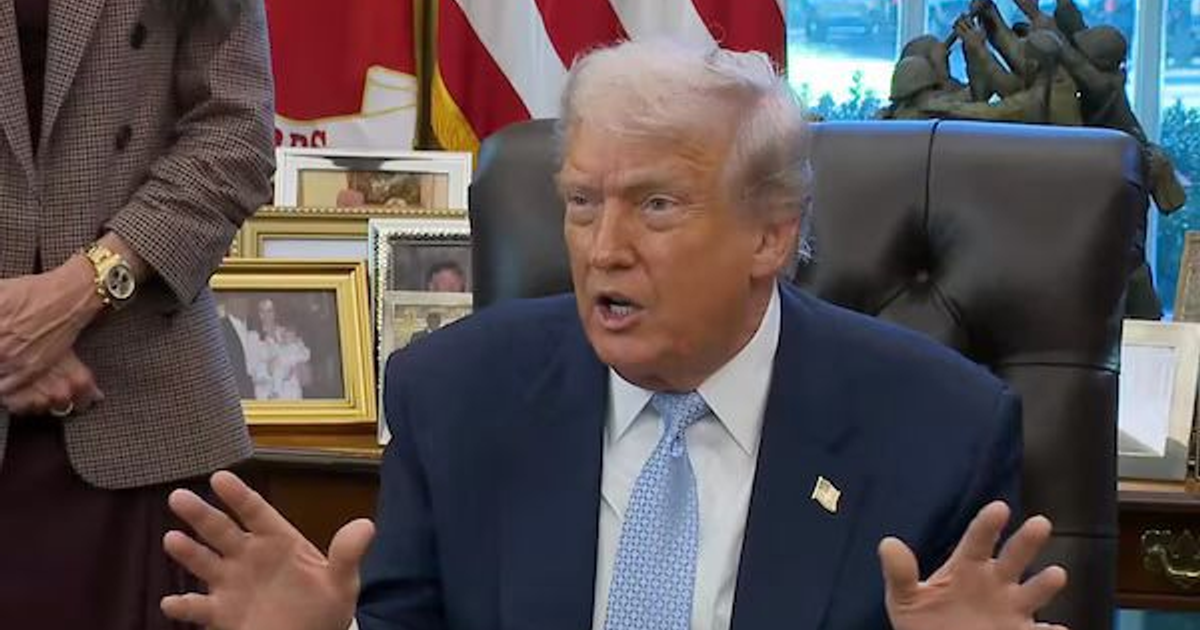 Personas conversando en una oficina con objetos decorativos y fotografías en el fondo.