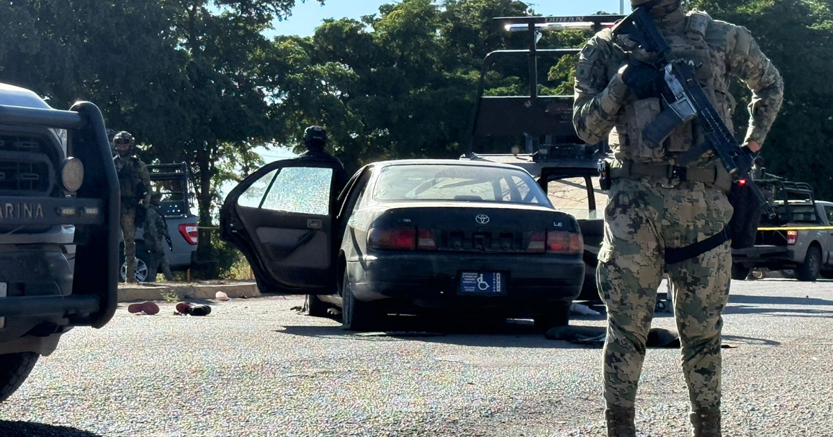 Oficial de seguridad vigilando un vehículo abierto tras enfrentamiento en Culiacán