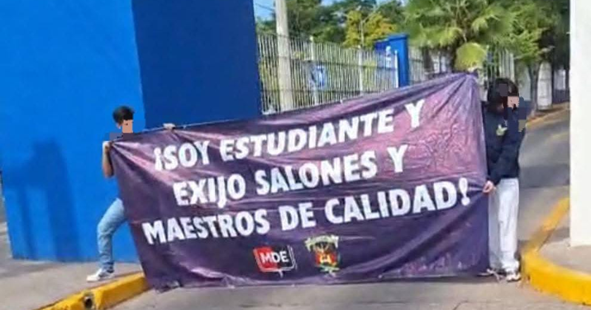 Dos estudiantes sosteniendo una pancarta que exige salones y maestros de calidad en la UAS.