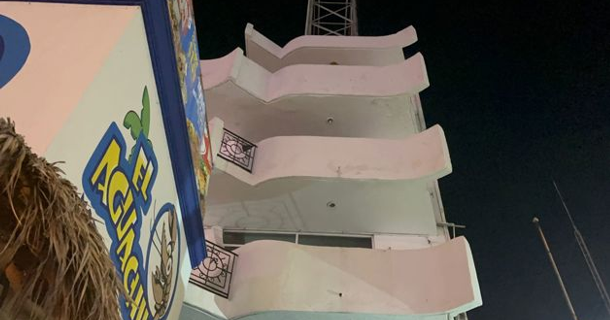 Edificio con balcones curvados y letrero de 'El Aguachile' en Mazatlán, tomado de noche.