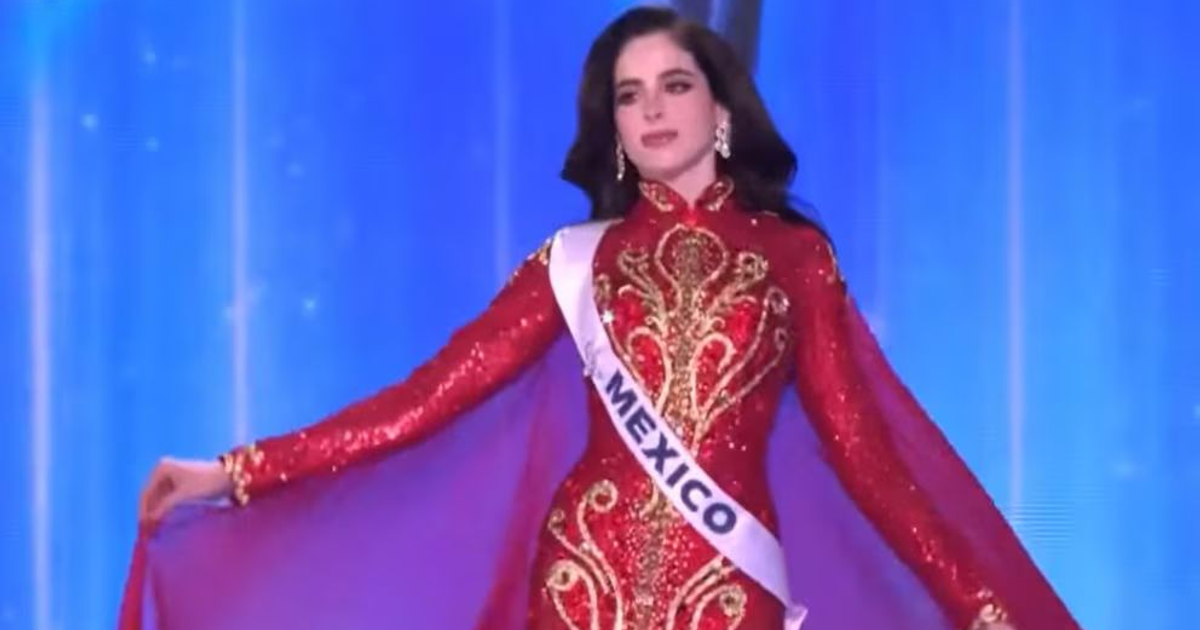 Fátima Bosch en atuendo rojo y dorado, coronada Miss Universo 2025, con banda 'MÉXICO' en un escenario azul.