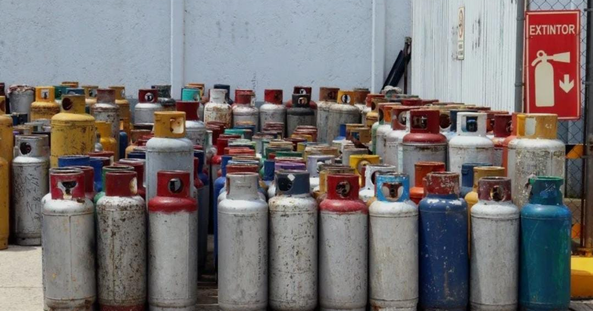 Cilindros de gas en diferentes colores y tamaños en un área abierta, con un extintor al fondo, reflejando el entorno crítico de almacenamiento de gas LP en México.