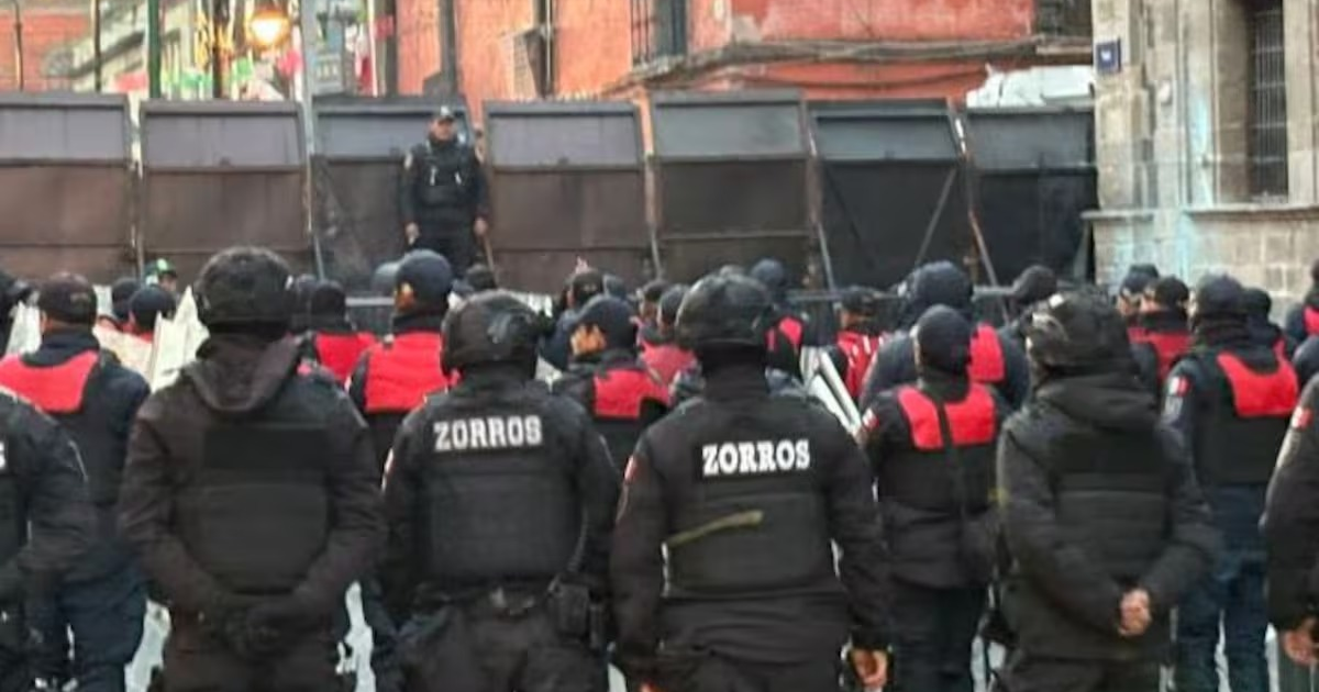 Agentes de seguridad en formación frente a una barrera durante una manifestación en CDMX