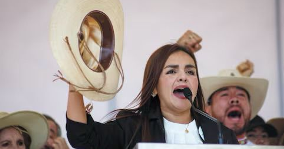 Grecia Quiroz hablando en mitin en Uruapan, sosteniendo un sombrero