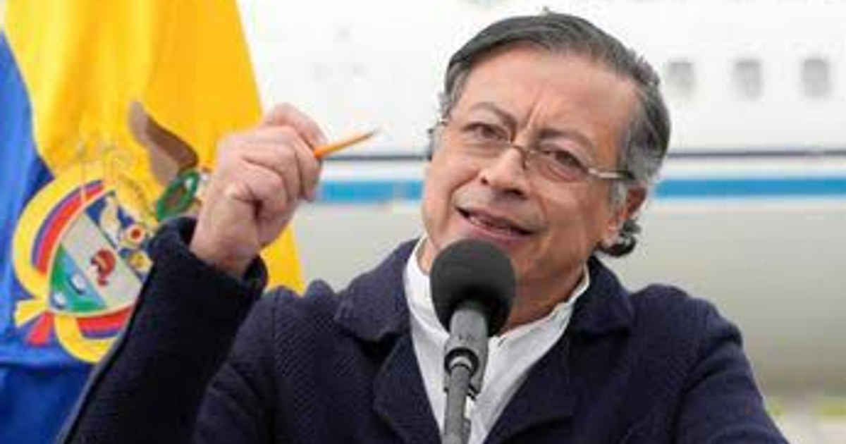 Gustavo Petro hablando en conferencia con bandera colombiana en segundo plano.