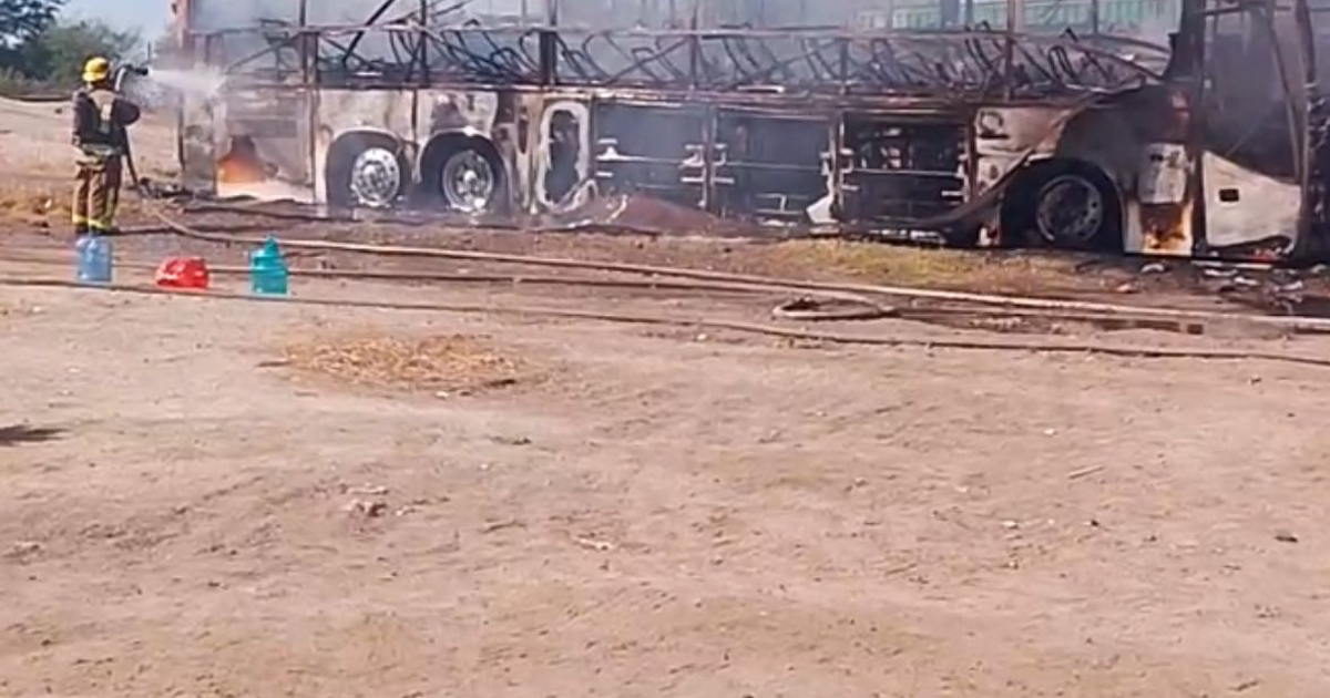 Autobús en llamas en la carretera México 15, Guasave, con bombero controlando el fuego.
