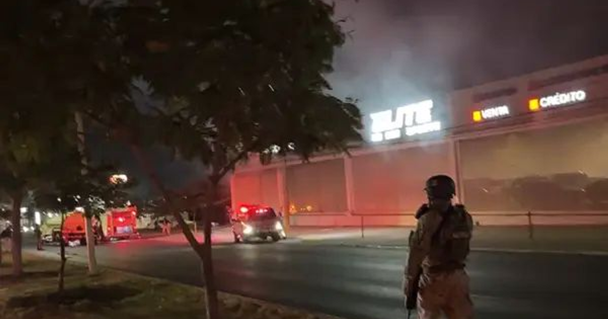 Vehículos envueltos en humo durante incidente nocturno en Culiacán con presencia policial.