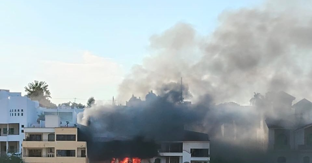 Edificio en llamas en Colinas de San Miguel, Culiacán, con humo negro y cielo despejado.