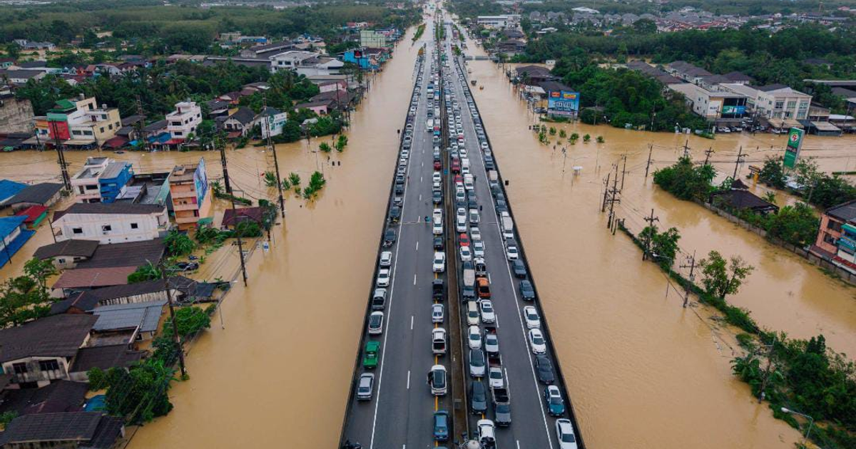 Escena de inundación en Hat Yai, Tailandia, con agua cubriendo una carretera y edificios.