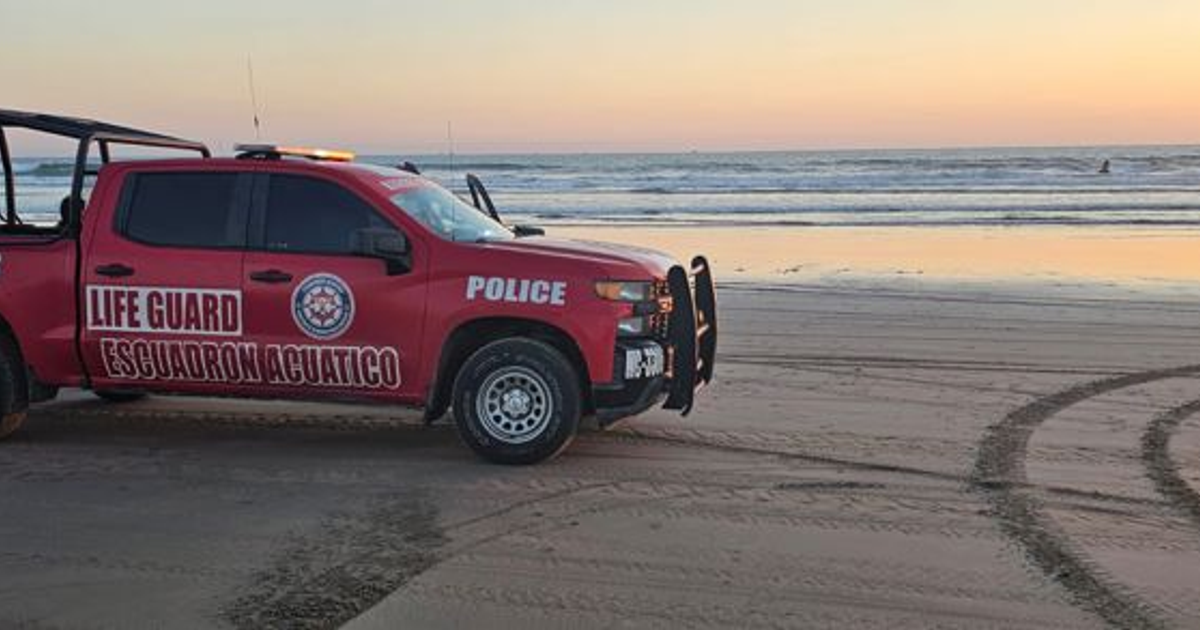 Camioneta roja de salvamento acuático en playa al atardecer