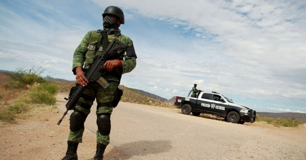 Soldado armado en operativo de la Guardia Nacional en Hermosillo, Sonora, con camioneta policial al fondo.
