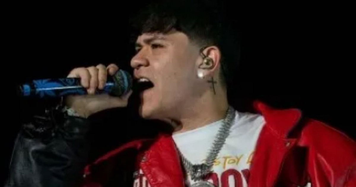 Cantante en concierto con chaqueta roja y micrófono en mano