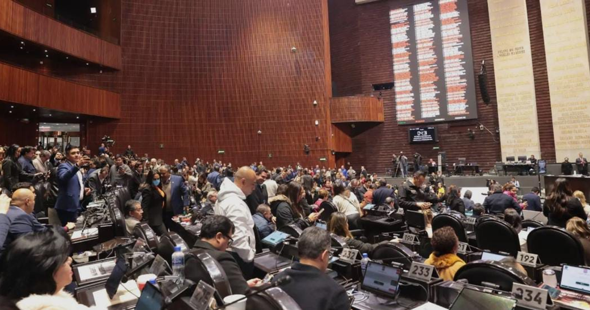 Legisladores debaten ley contra extorsión en una asamblea, con tecnología y resultados en pantalla.