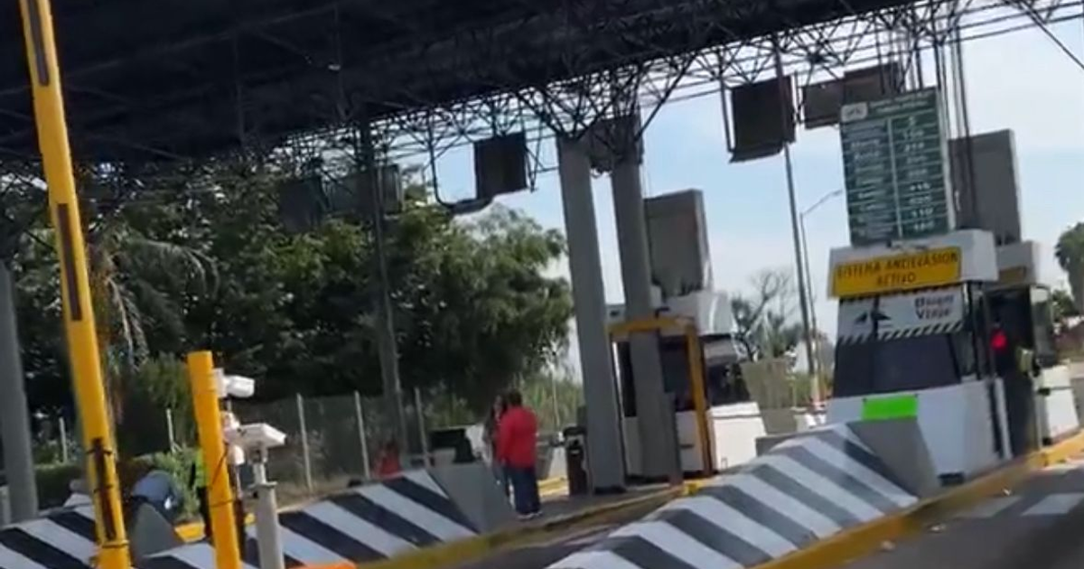 Vista de una caseta de cobro liberada temporalmente en Culiacán, Sinaloa, con personas y vehículos presentes bajo un cielo despejado.