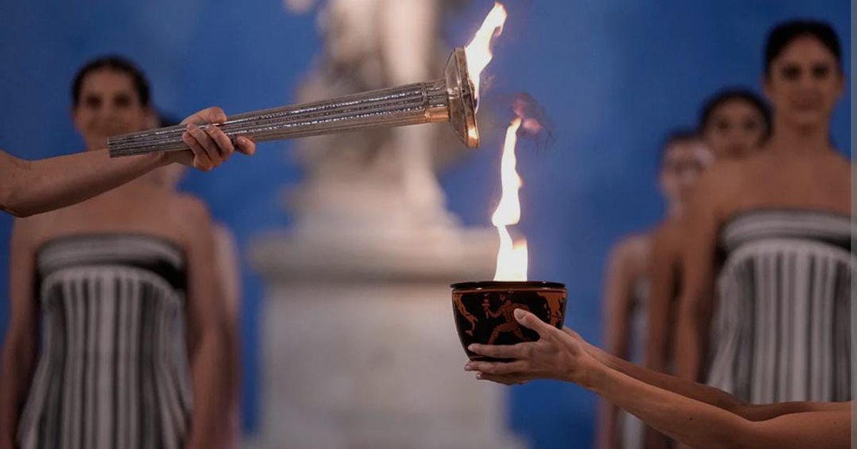 Portador con antorcha olímpica encendiendo un cuenco durante la ceremonia de encendido en Olimpia